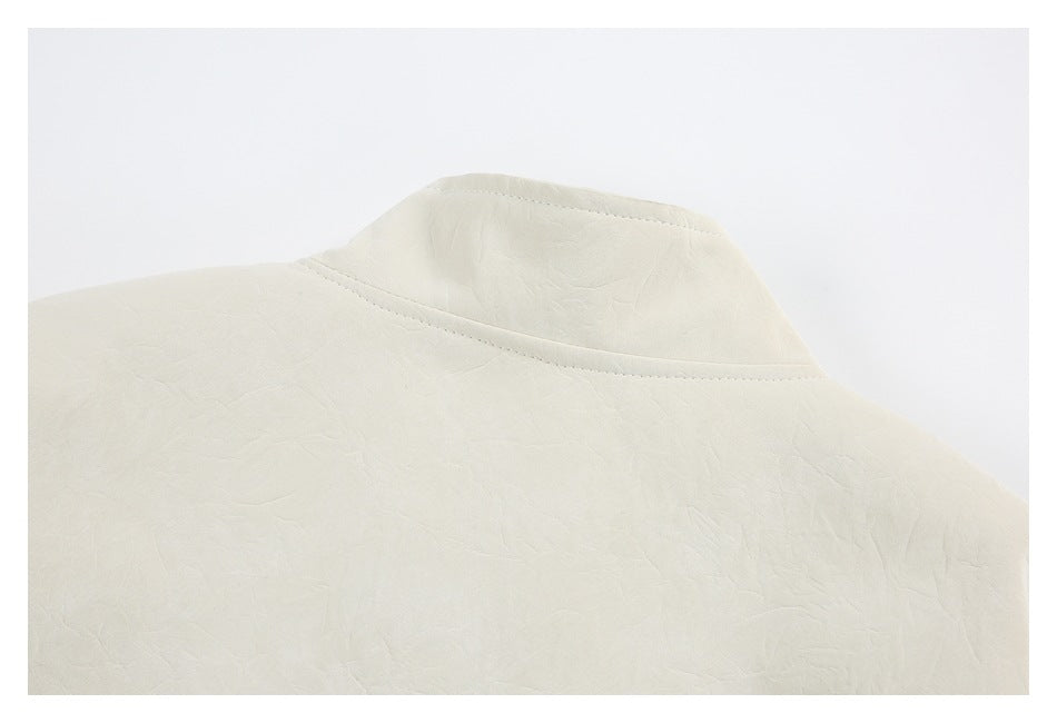 Close-up of an ivory garment collar and surrounding fabric with visible stitching and a softly creased surface.