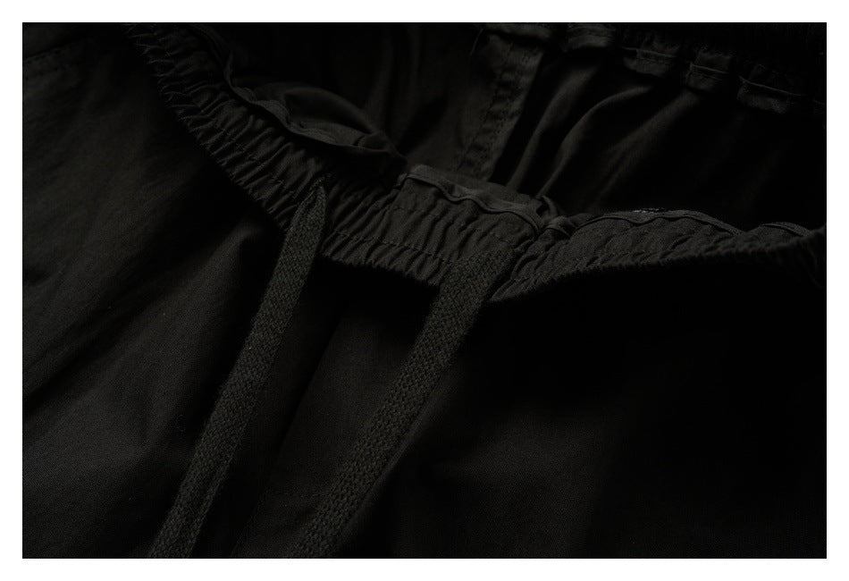 Close-up of black pants showing the gathered elastic waistband and two drawstrings.