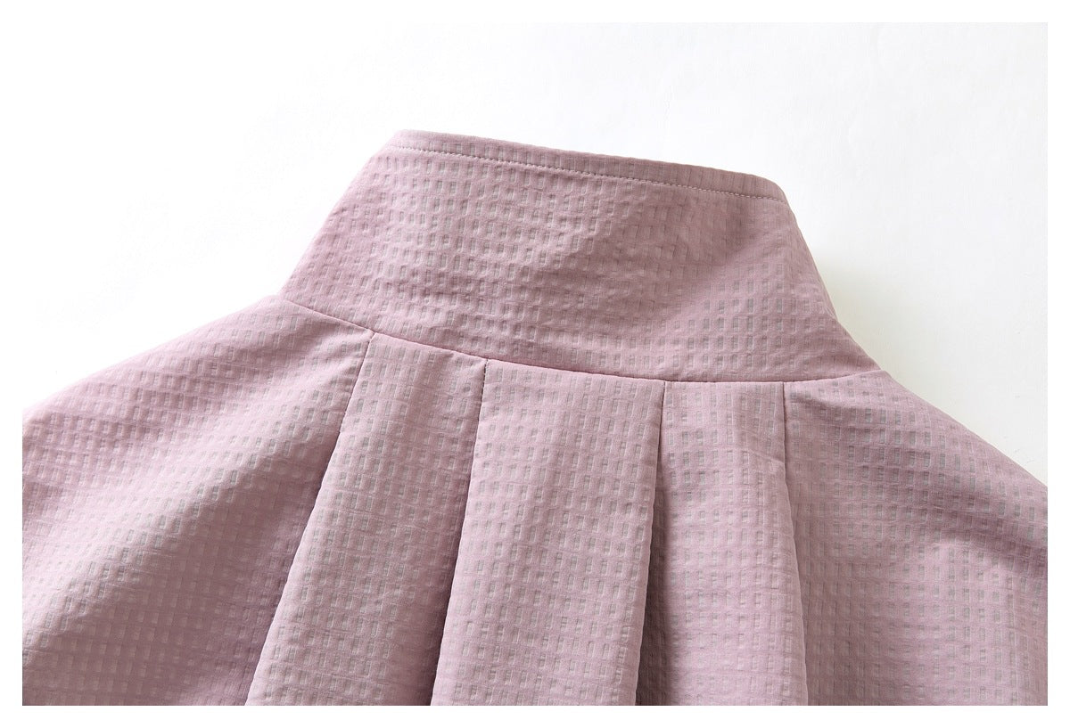 Close-up of a dusty pink garment’s high waistband and wide pleats.
