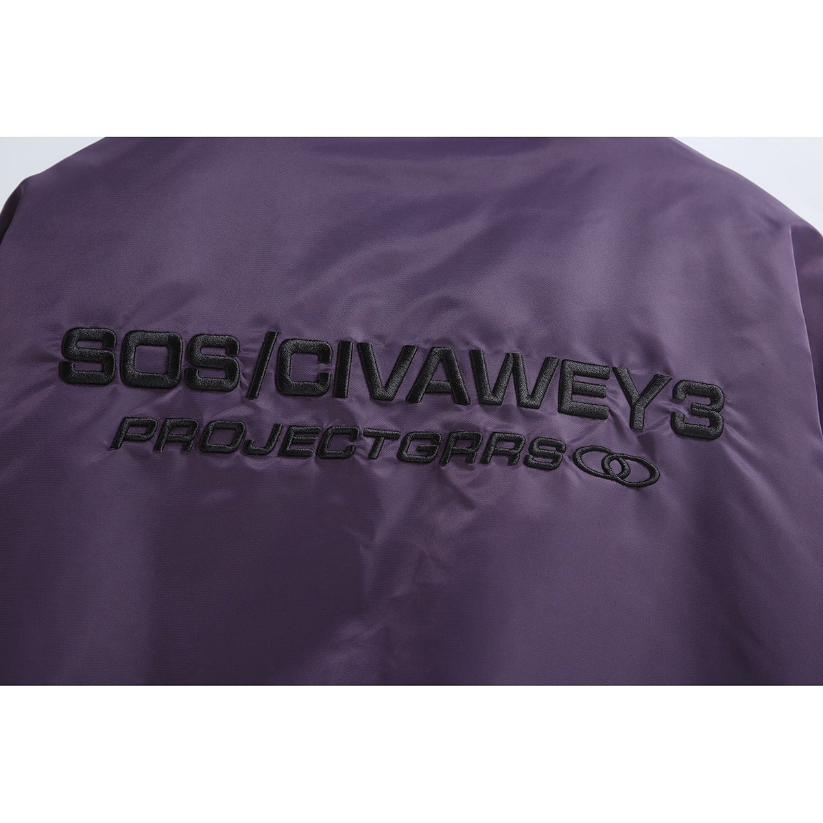 Close-up of black embroidered lettering across the back of a purple bomber jacket.