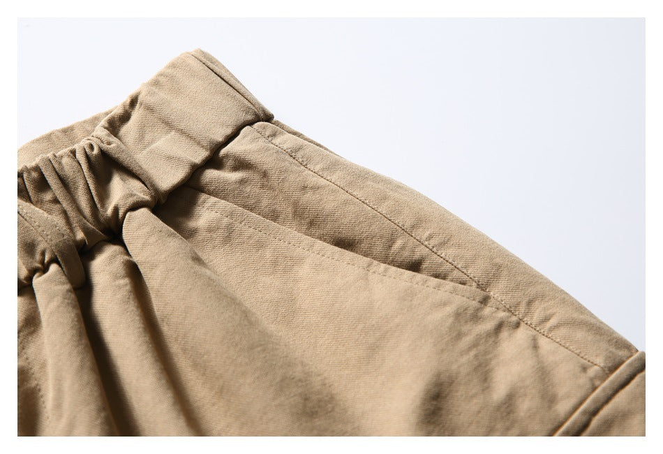 Close-up of a tan shorts pocket opening, waistband, and stitched seams.