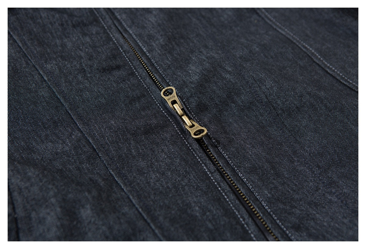 Close-up of a dark indigo garment with a brass-colored zipper and contrast stitching.