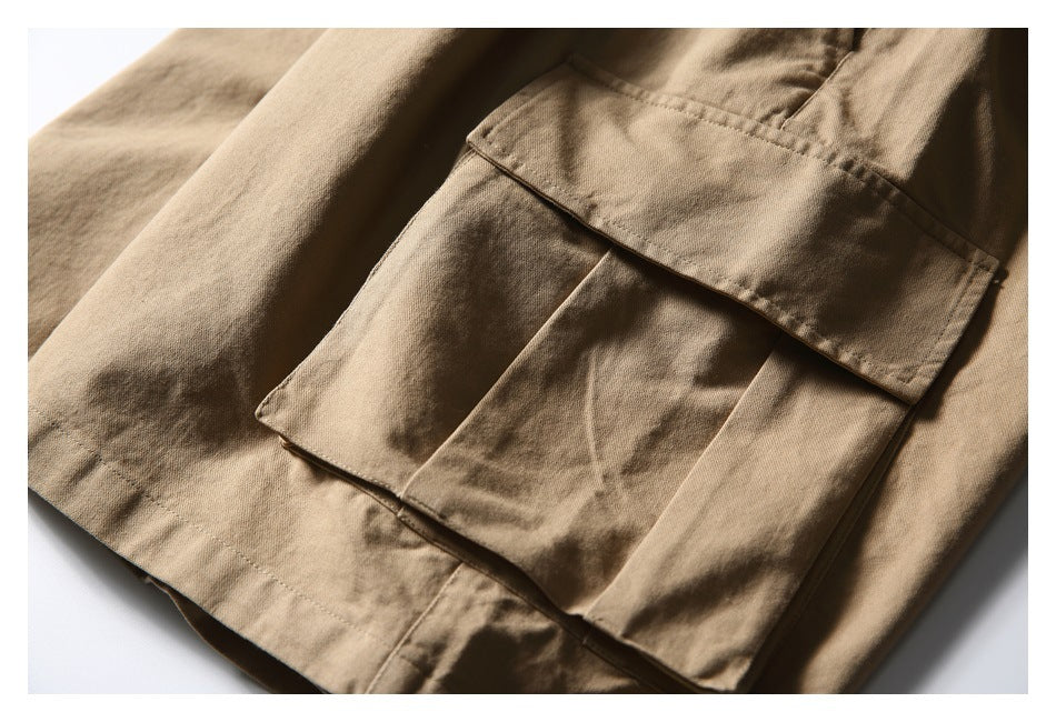 Close-up of a large layered flap cargo pocket on tan trousers.