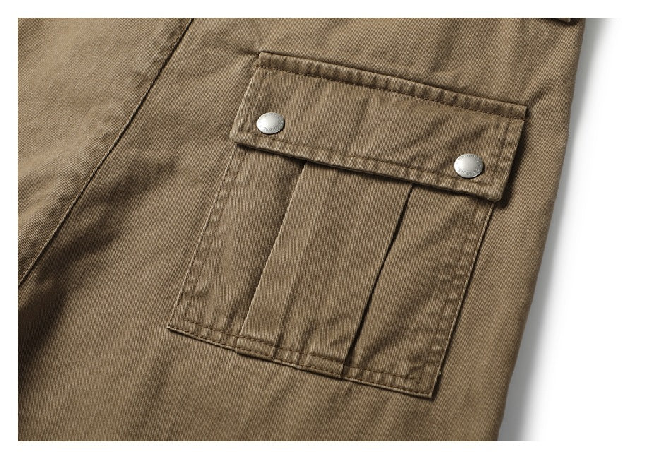 Close-up of a pleated cargo pocket with a snap-button flap on khaki-brown trousers.