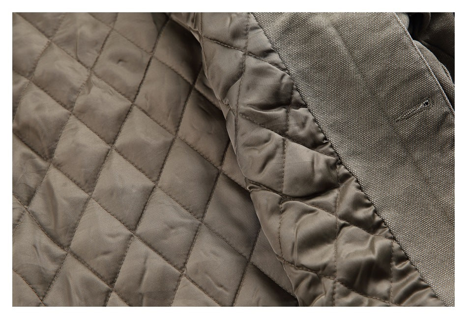 Close-up of taupe-brown diamond quilting and a seam beside dark textured fabric.