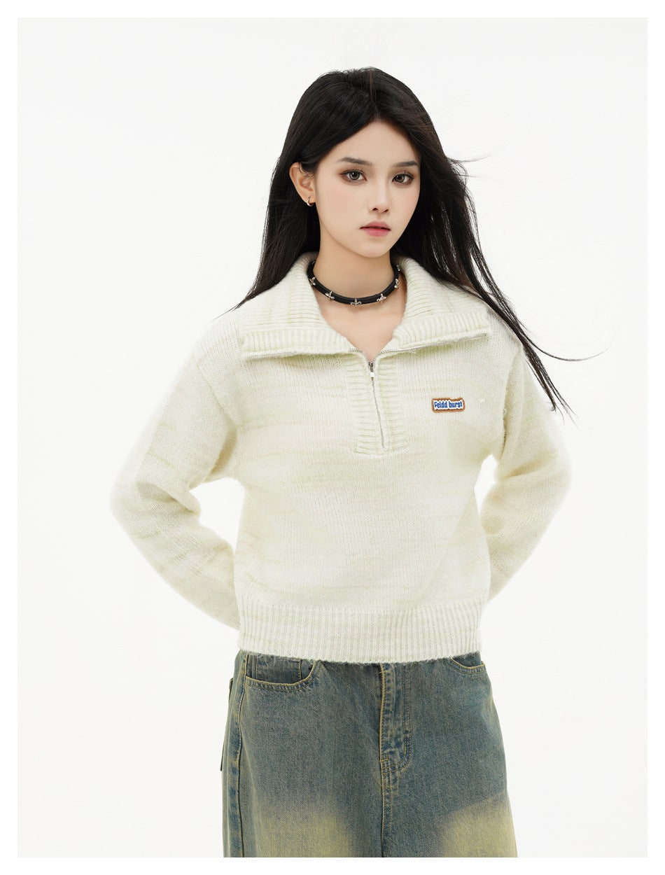 Front view of a model wearing an ivory knit quarter-zip pullover with a wide ribbed collar.