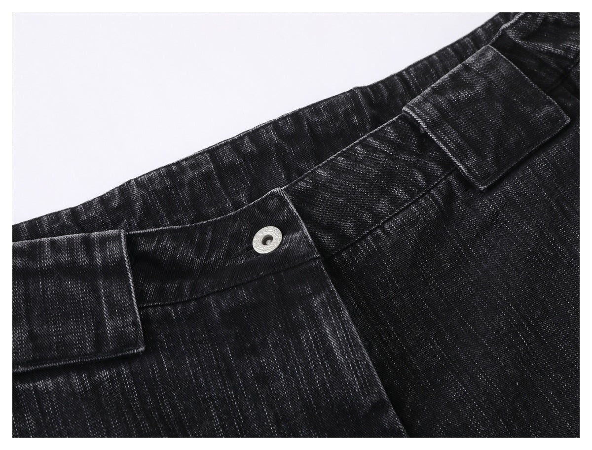 Close-up of black denim trousers showing the waistband, silver button, and belt loops.