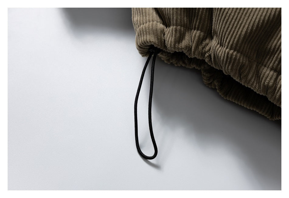 Close-up of the gathered hem of a brown corduroy jacket with a black drawcord.