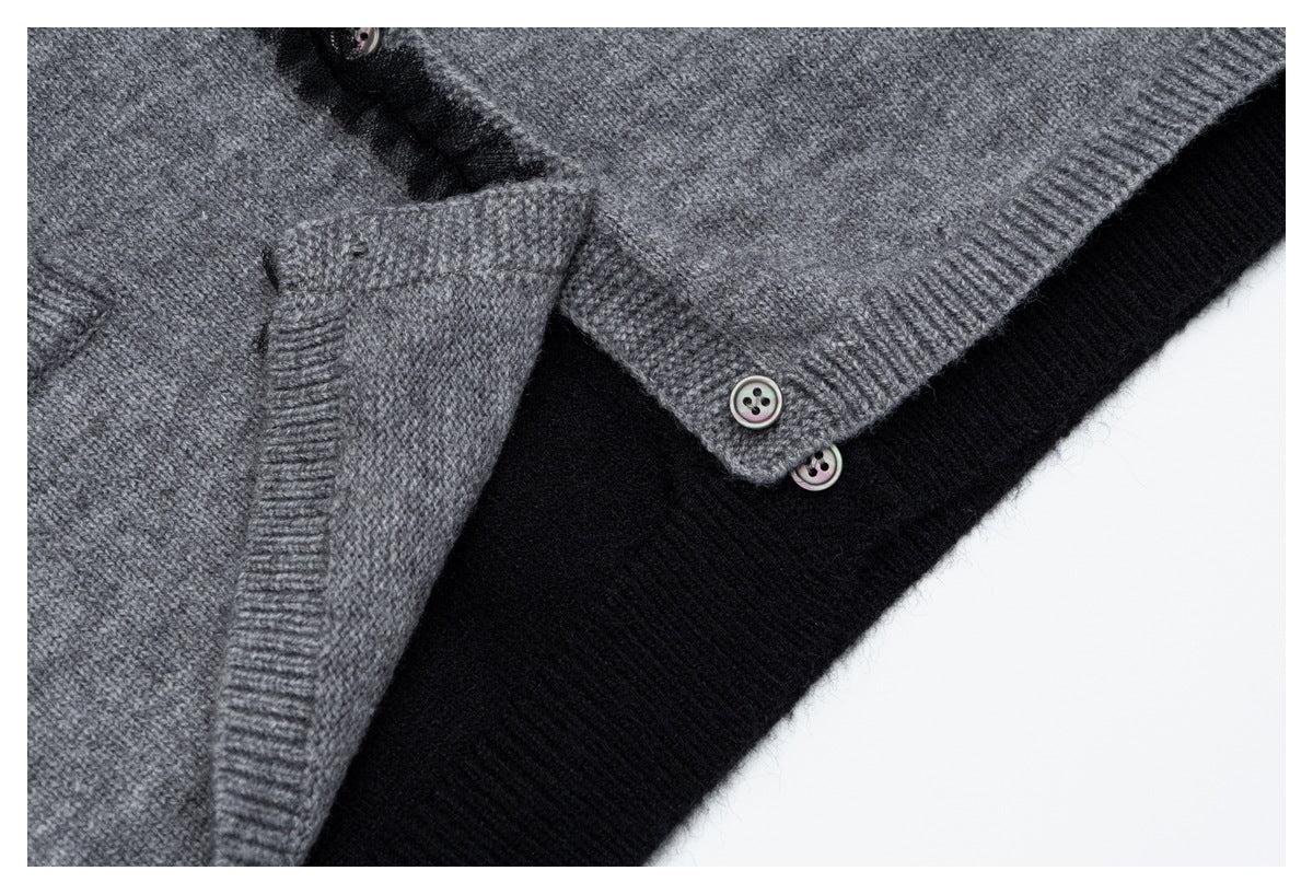 Close-up of the gray cardigan's buttoned hem and front opening layered over black knit fabric.