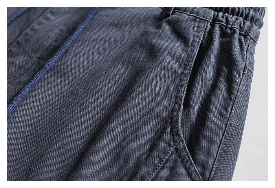 Close-up of slate blue trousers showing the side pocket seam, gathered elastic waistband, and fabric texture.