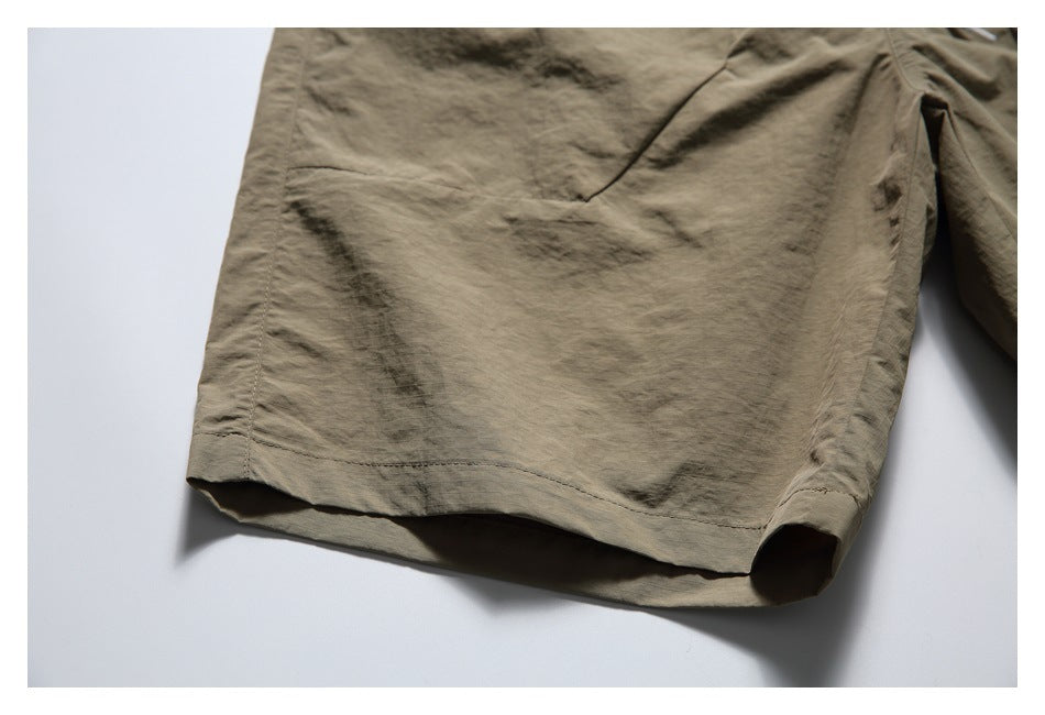 Close-up of the olive-khaki shorts leg, showing its stitched hem and side seam.