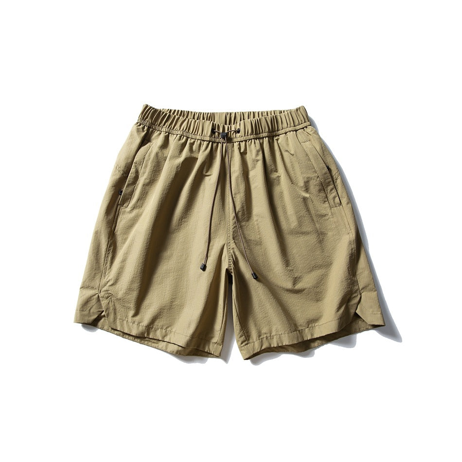 Khaki drawstring shorts with elastic waistband, side pockets and curved side-slit hems, flat lay