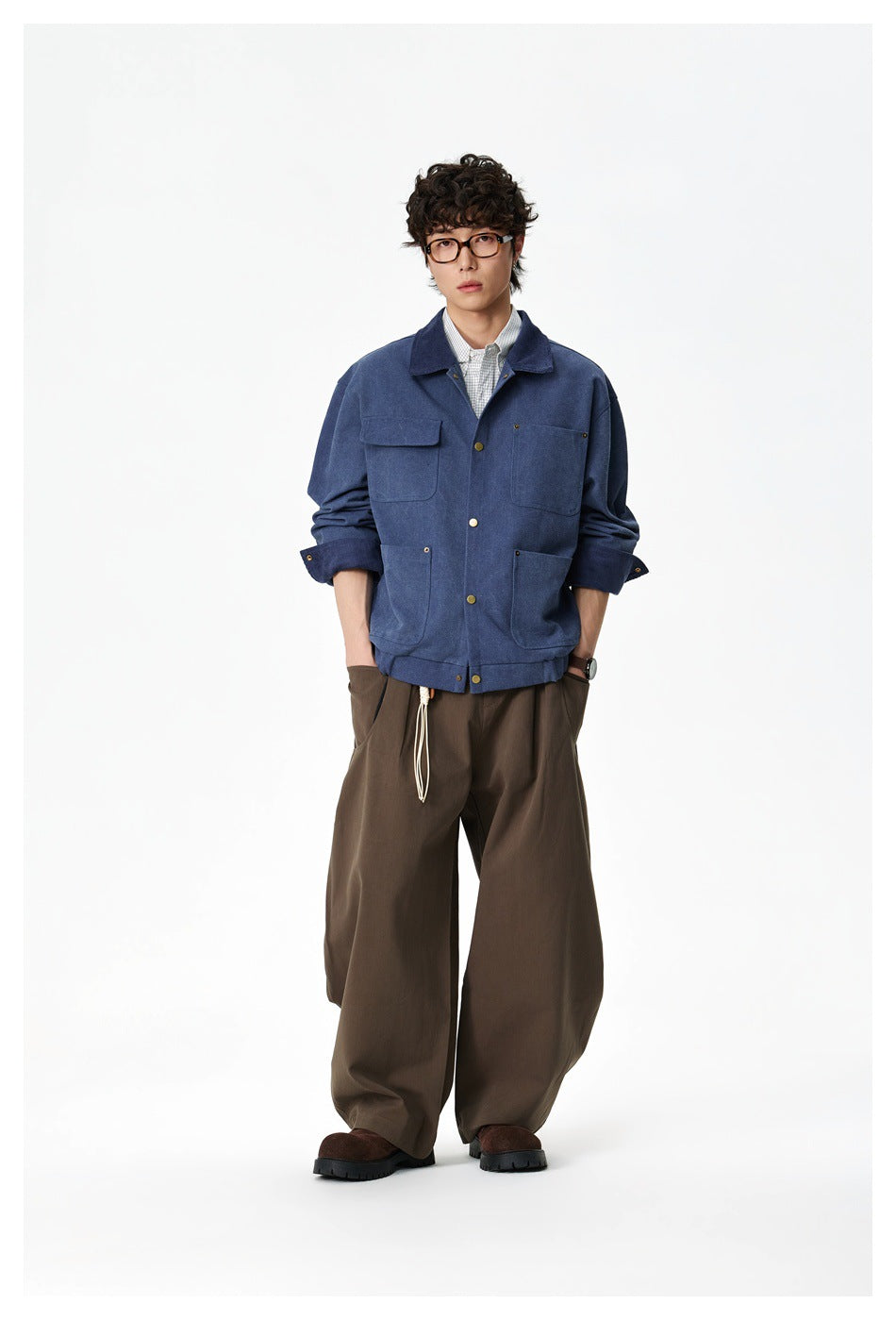 Full-length model wearing a blue four-pocket jacket, checked shirt, and wide brown trousers.