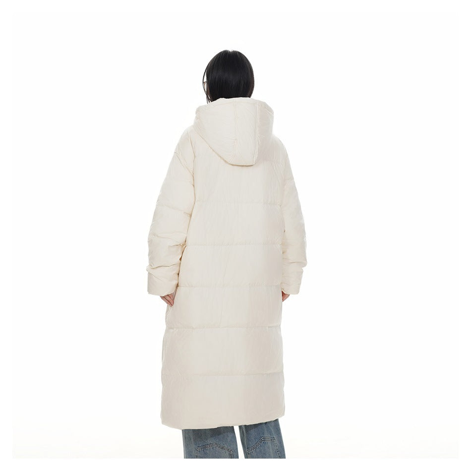 Back view of a model wearing a long ivory quilted puffer coat with a hood.