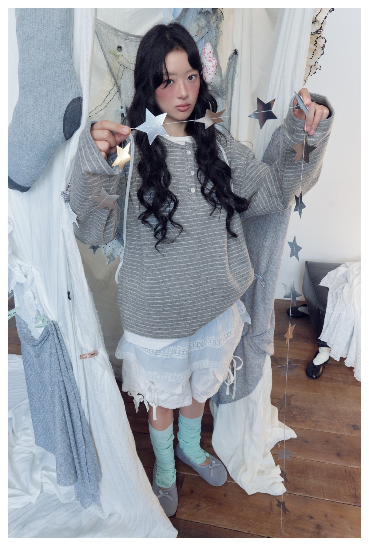 Model wearing an oversized gray-and-white striped button-front top, layered pale blue skirt and white shorts.