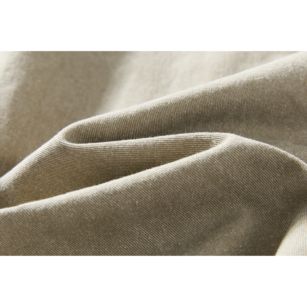 Extreme close-up of the beige shorts’ textured fabric and folded seam.