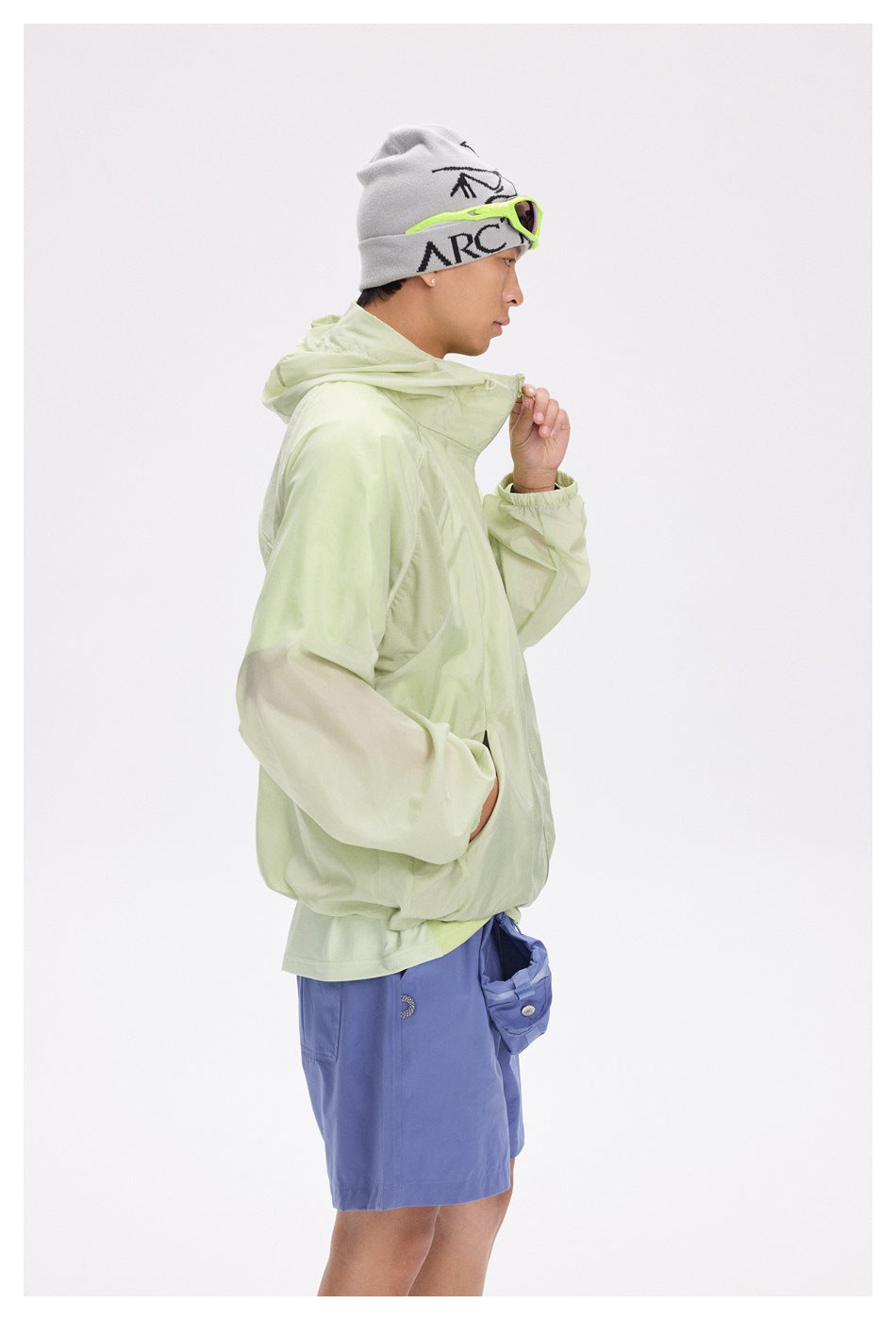 Side view of a man modeling a pale lime hooded zip jacket with elastic cuffs.