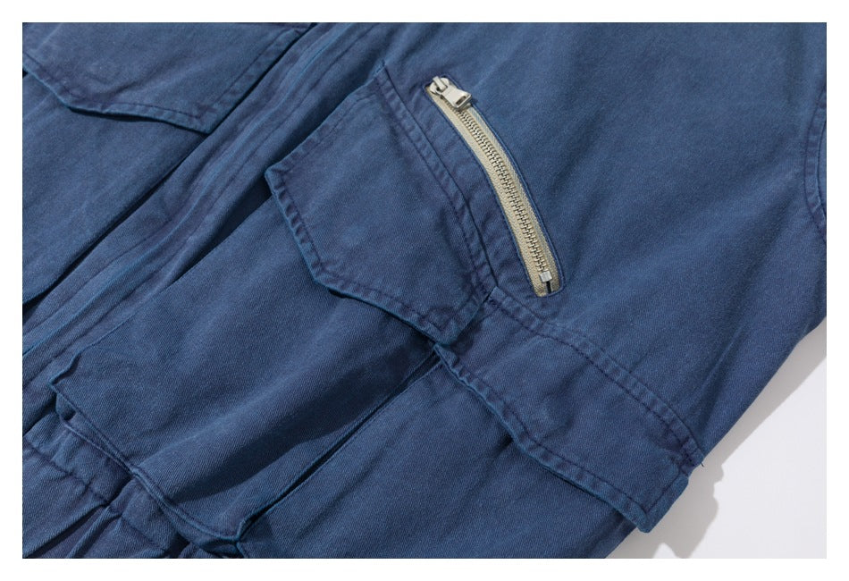 Blue garment detail showing a flap pocket beside a short metal zip pocket.