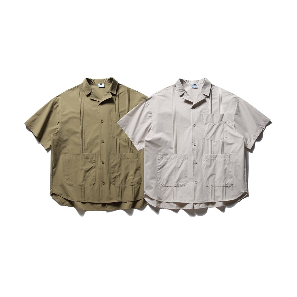 Two short-sleeve button-up shirts displayed side by side in olive and pale beige, each with multiple front pockets.