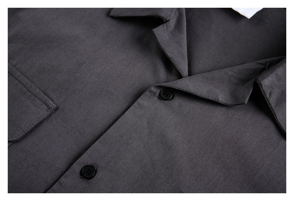Close-up of the charcoal shirt’s pointed collar, black buttons, fabric, and pocket edge.