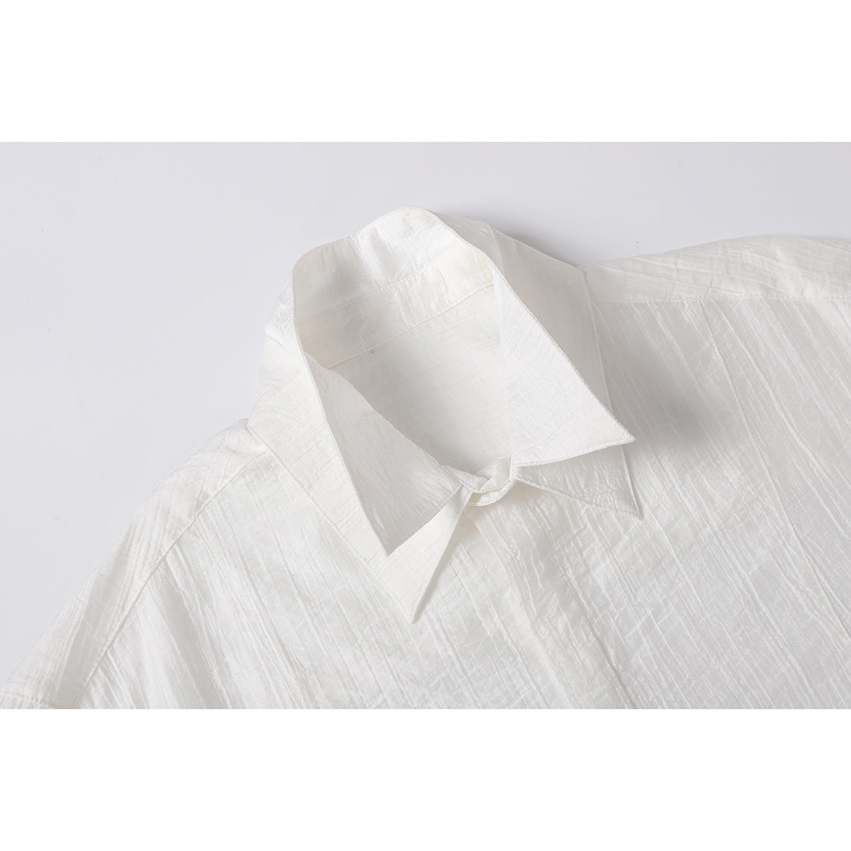 Close-up of a white short-sleeve shirt's pointed collar and textured fabric.