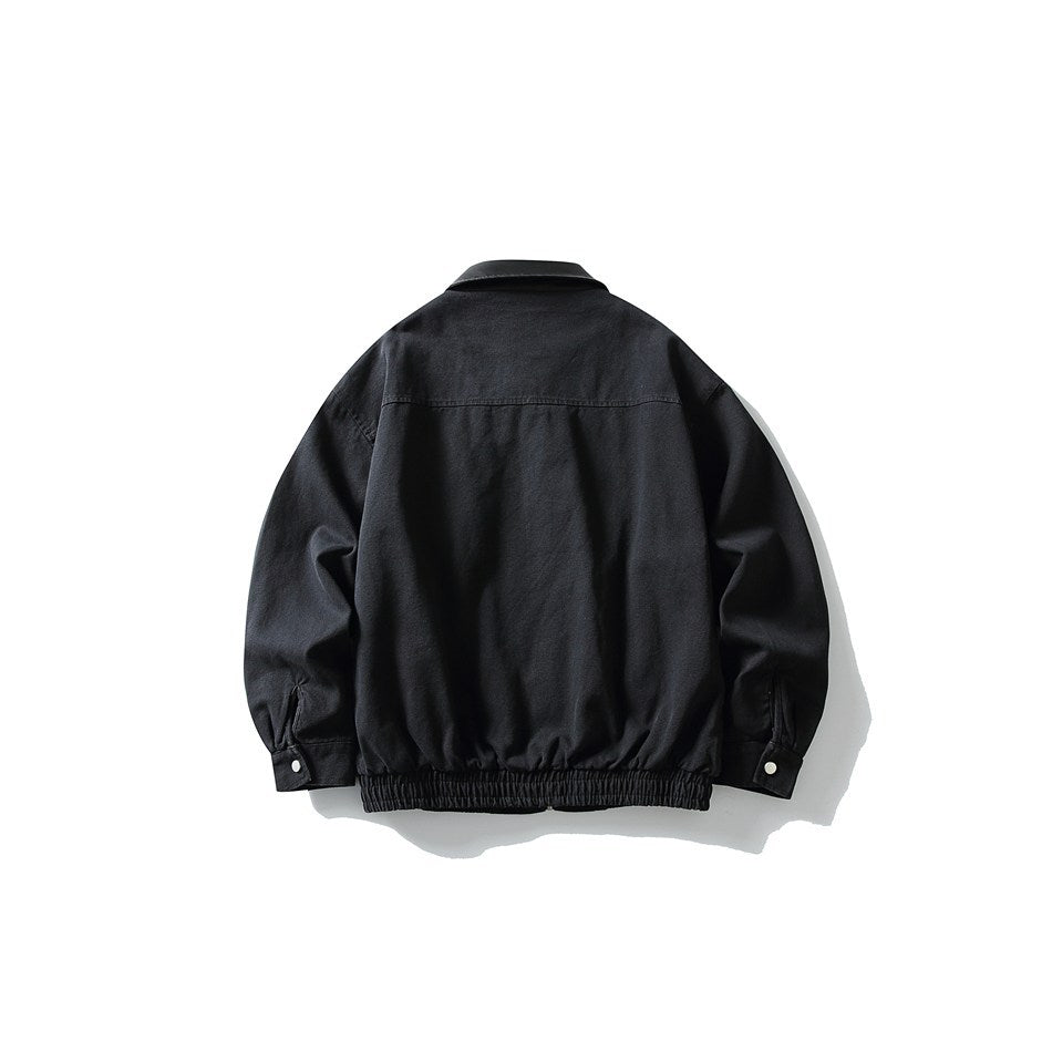 Back view of black collared jacket with horizontal yoke seam, elastic hem and snap-button cuffs, flat lay