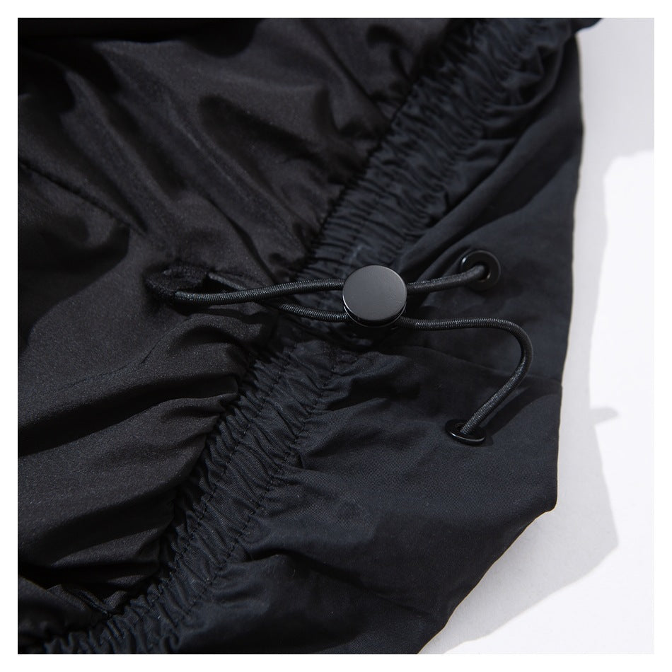Close-up of a black garment's gathered elastic edge with an adjustable cord and stopper.