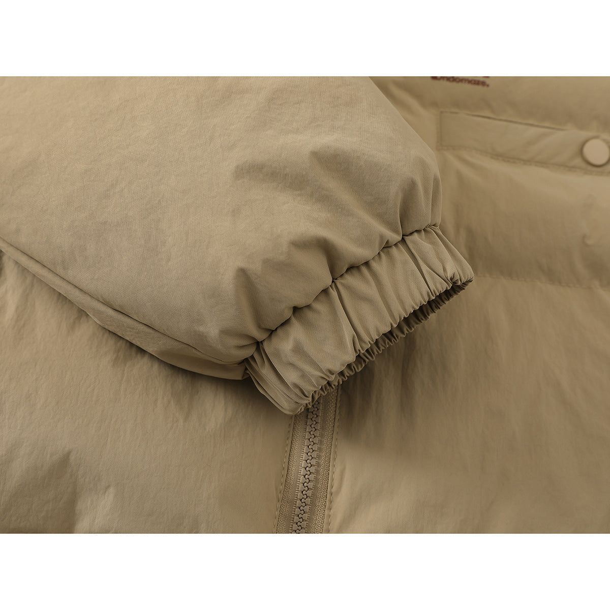 Close-up of a tan padded jacket sleeve with an elasticated cuff over the front zipper.