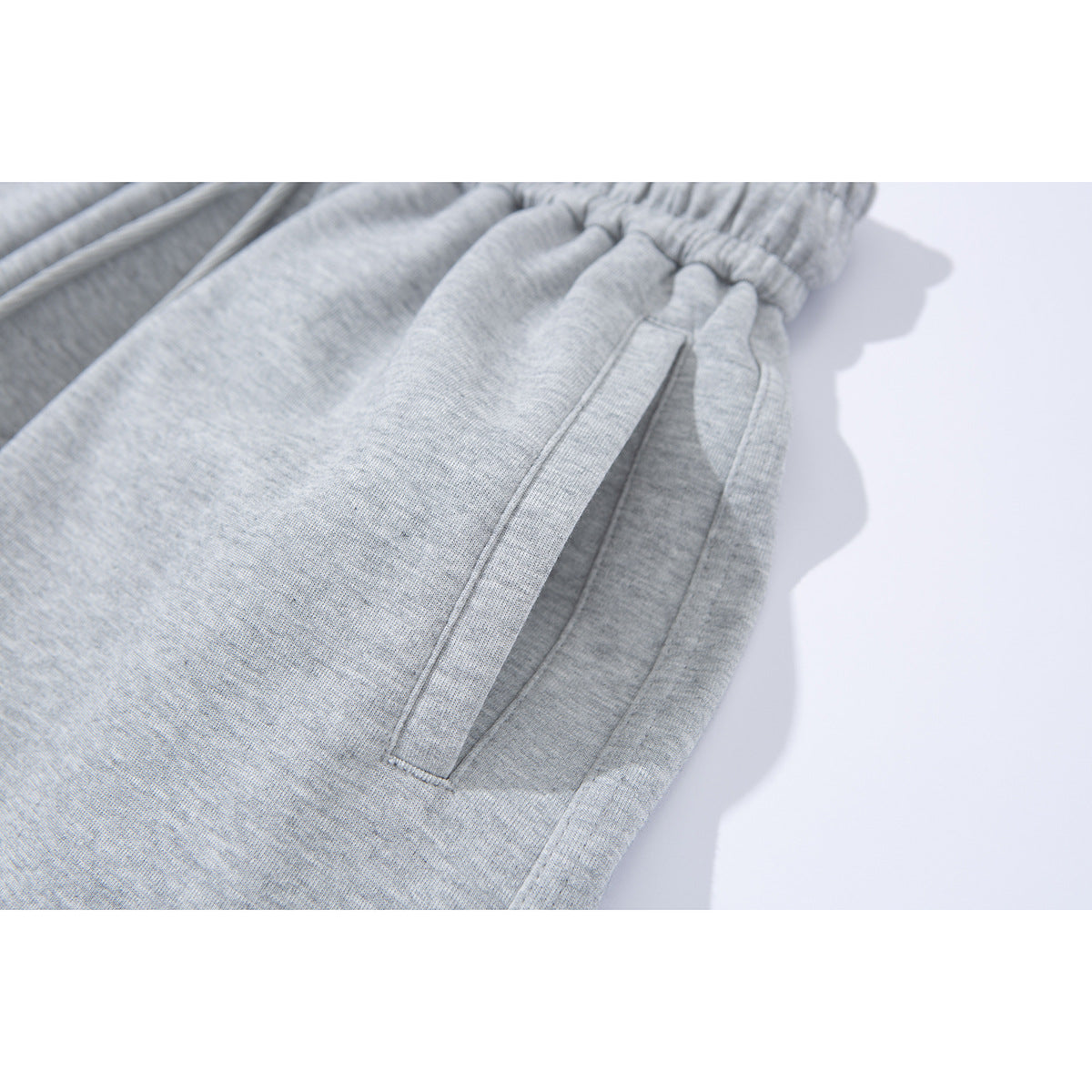 Close-up of a slanted side pocket on light gray sweatpants.