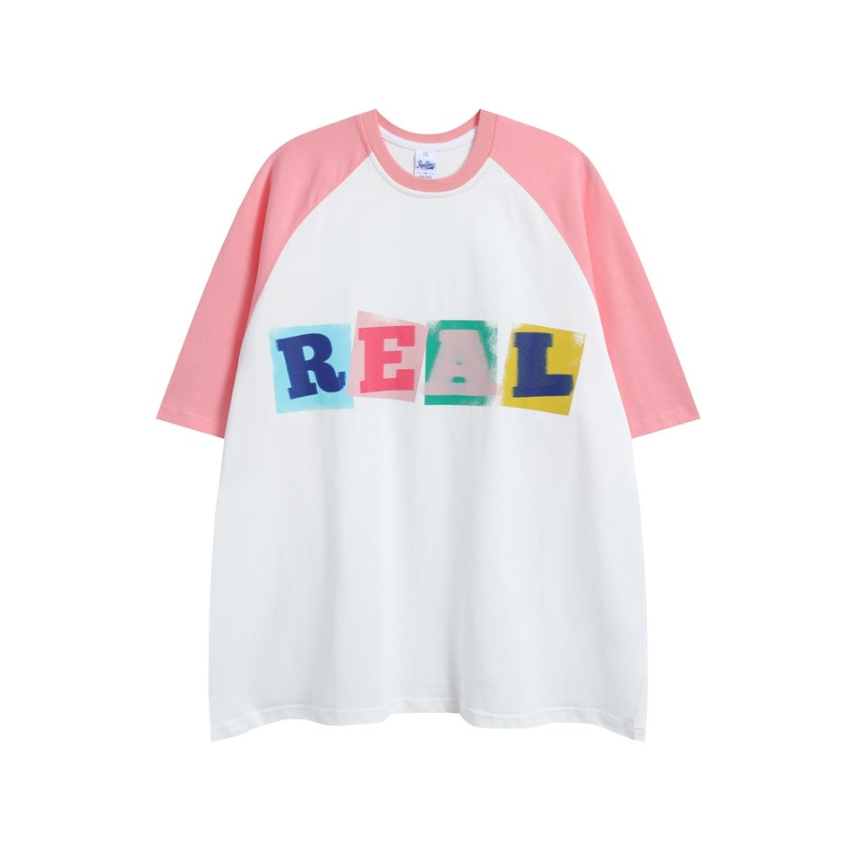 White raglan T-shirt with pink sleeves and collar and a multicolor block-letter REAL print on the chest