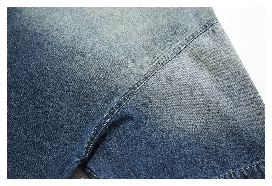 Close-up of a diagonal stitched seam across faded blue denim fabric.