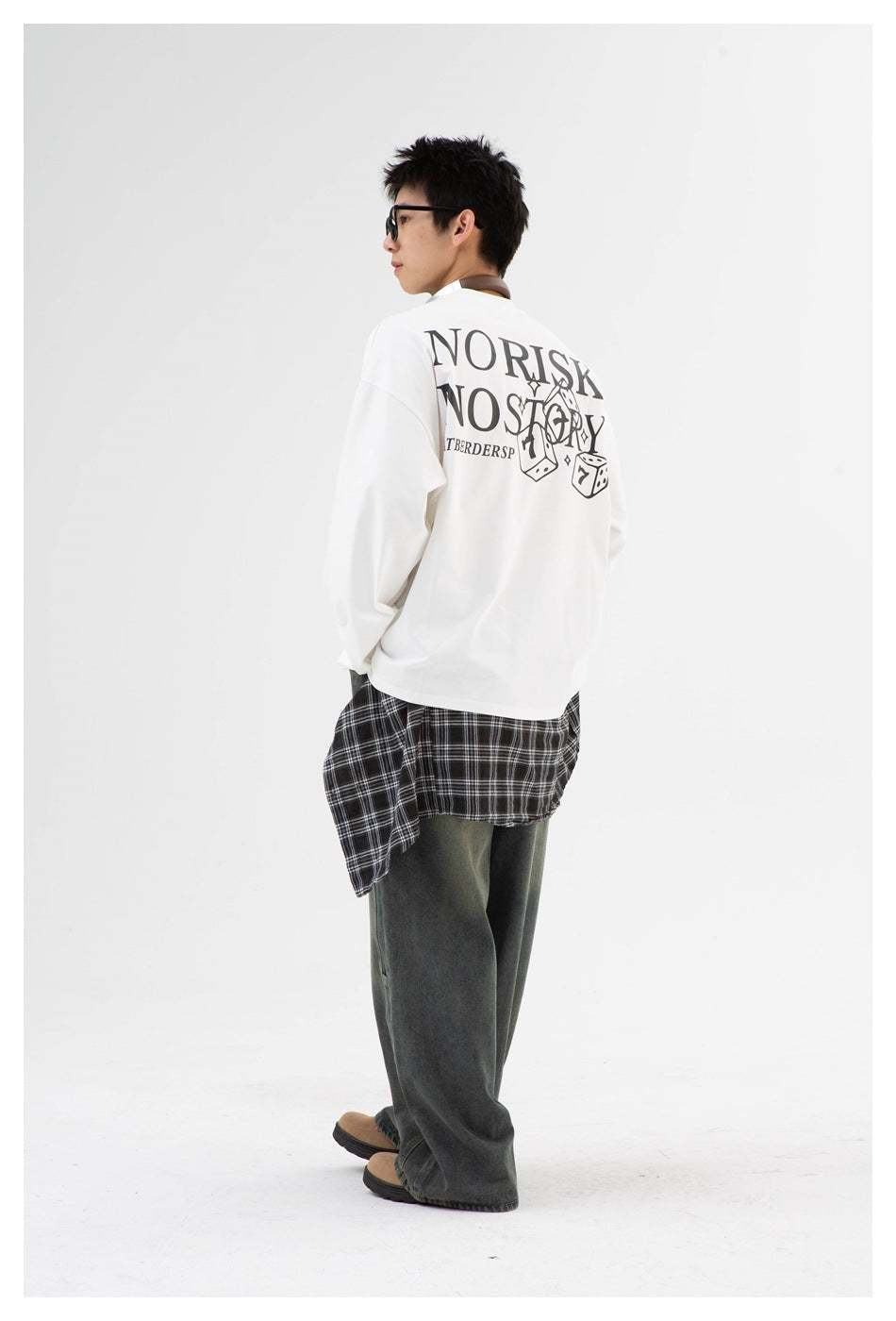 Side-rear view of a model wearing a white long-sleeve shirt with a large black text-and-dice back graphic.