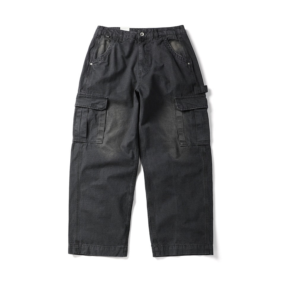 Front flat lay of washed black wide-leg cargo pants with flap side pockets and a button zip fly