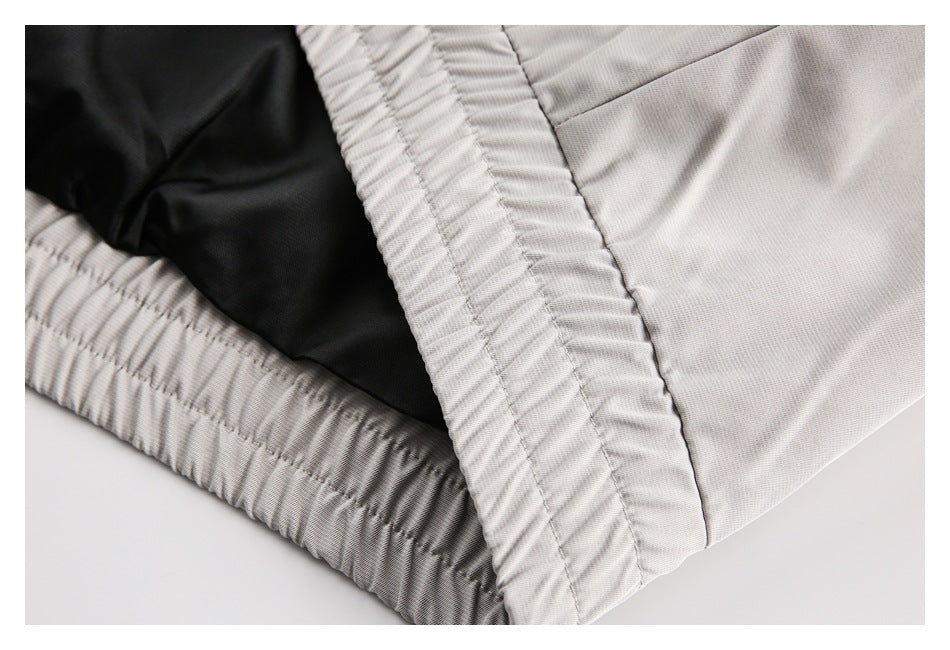 Close-up of a gathered elastic waistband and dark inner lining on light gray apparel.