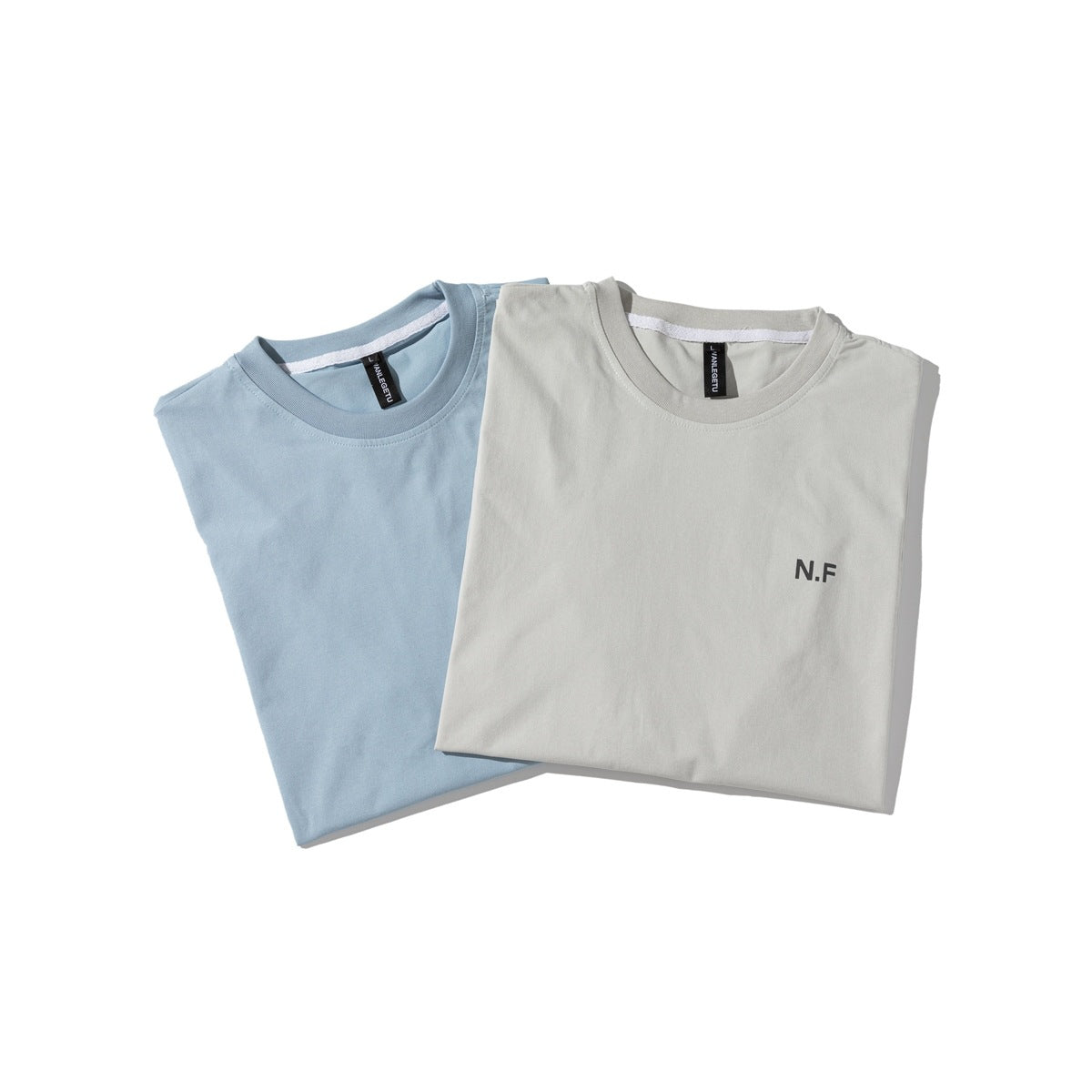 Light blue and light gray T-shirts folded together, with the gray shirt's small N.F chest print visible.