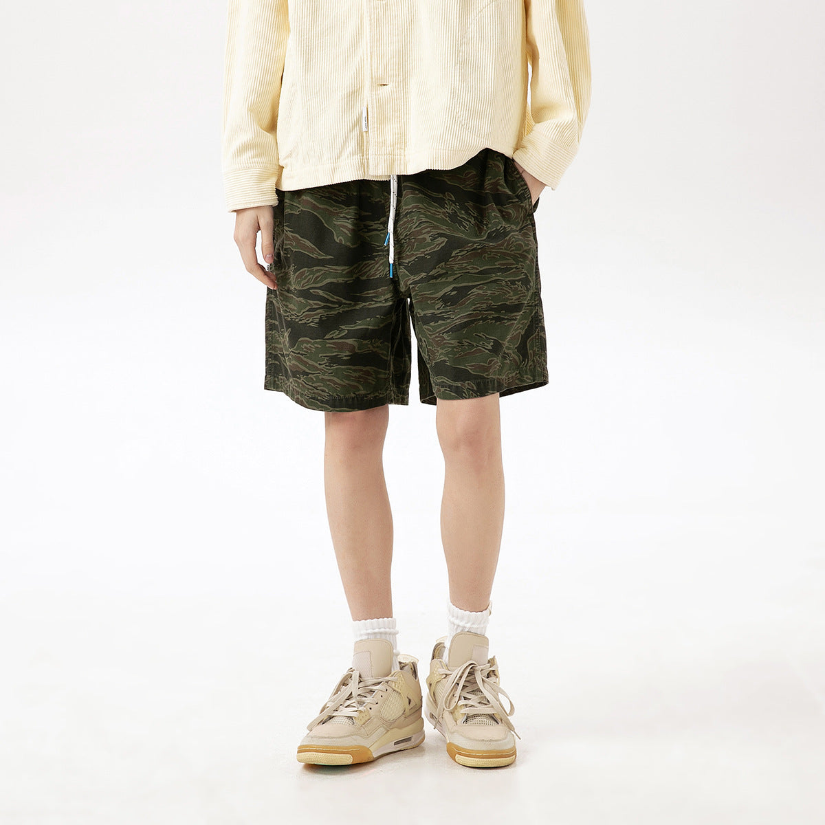 Model wearing olive camouflage drawstring shorts, shown from the front with the waistband partly covered.