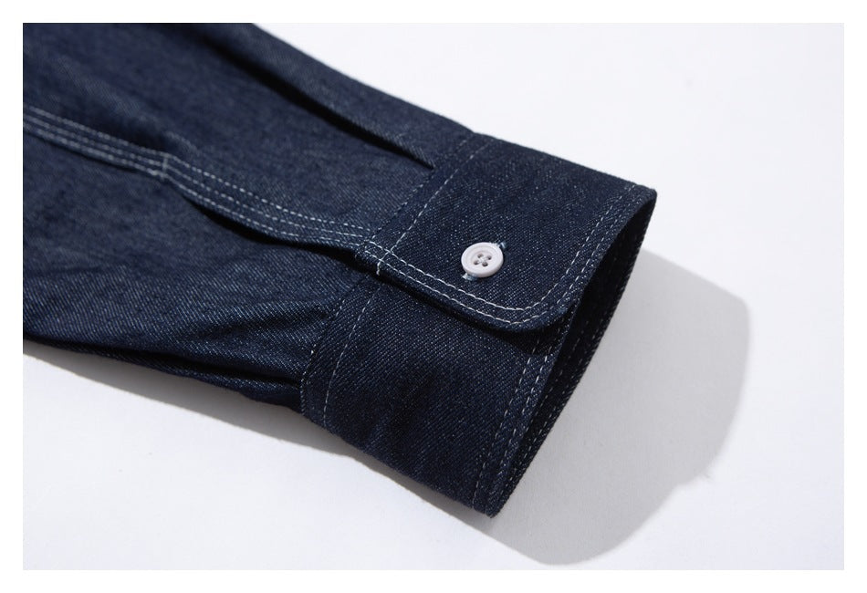 Close-up of a dark indigo shirt cuff with a white button and rows of contrast stitching.