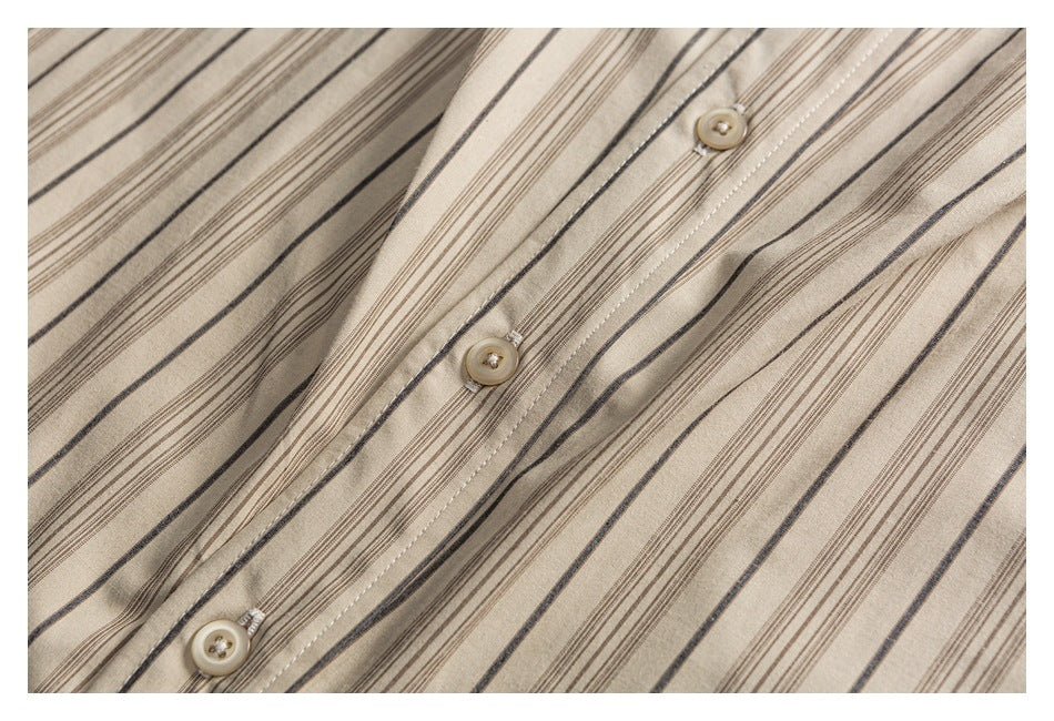 Close-up of a beige striped shirt's button placket with three light-colored buttons.
