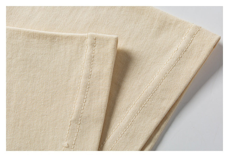 Close-up of a light beige knit garment hem with parallel rows of stitching.