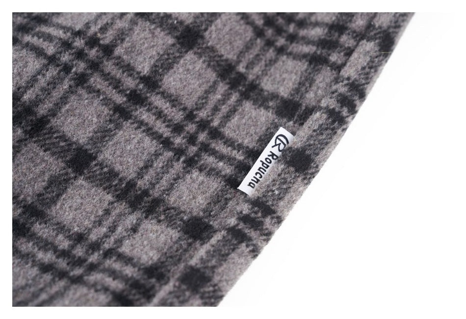 Close-up of gray and black plaid fabric with a small sewn brand label at the edge.