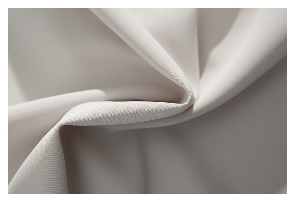 Close-up of off-white fabric arranged in soft folds, showing its surface texture.