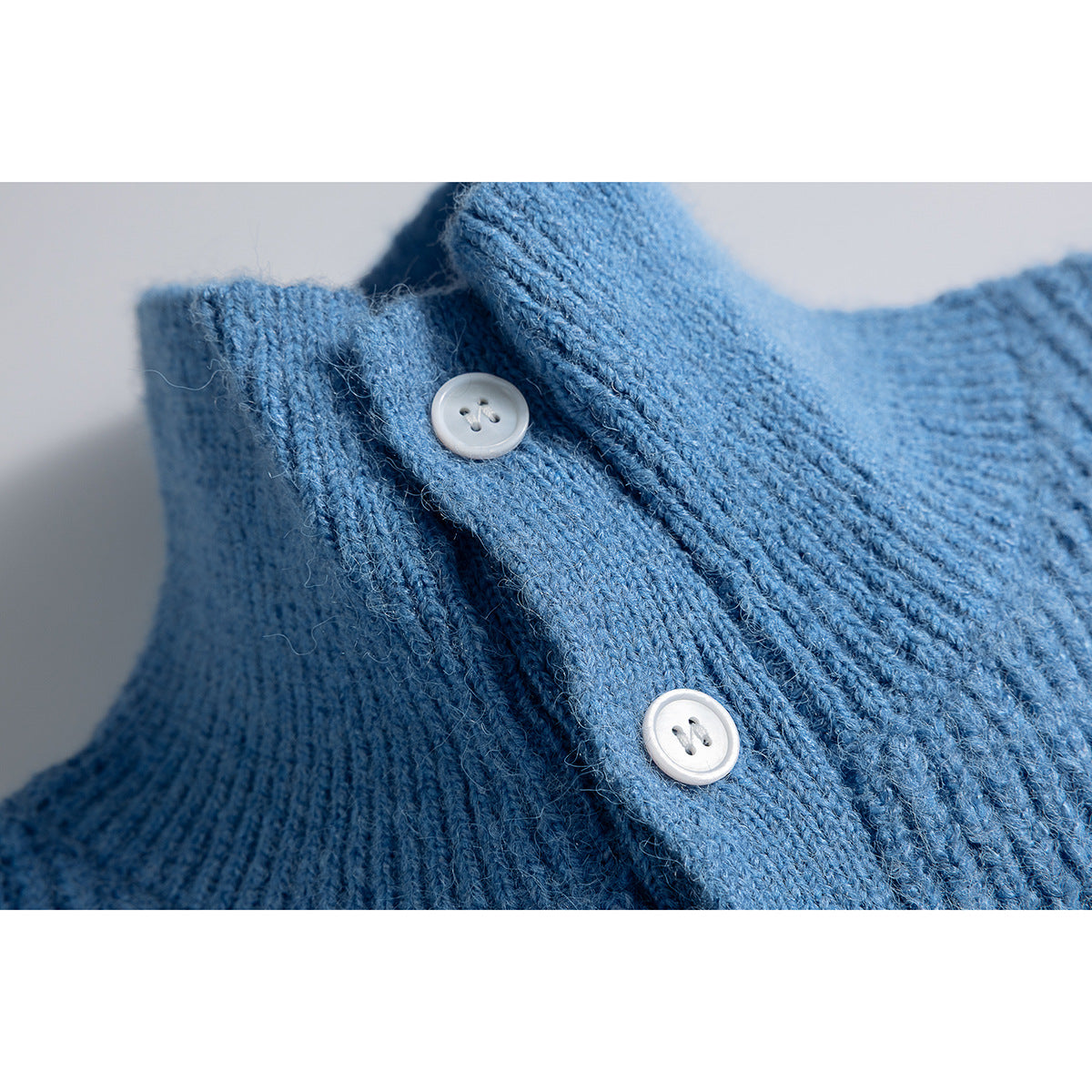 Close-up of a blue knit vest's collar and placket with two white buttons.