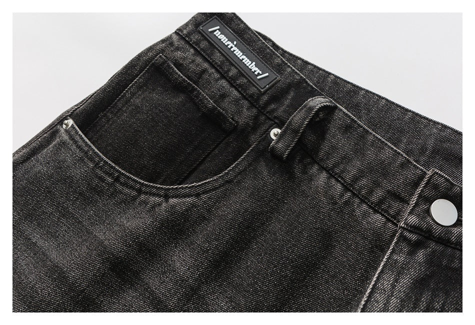 Angled close-up of the waistband, belt loop, button and front pocket on washed black jeans.