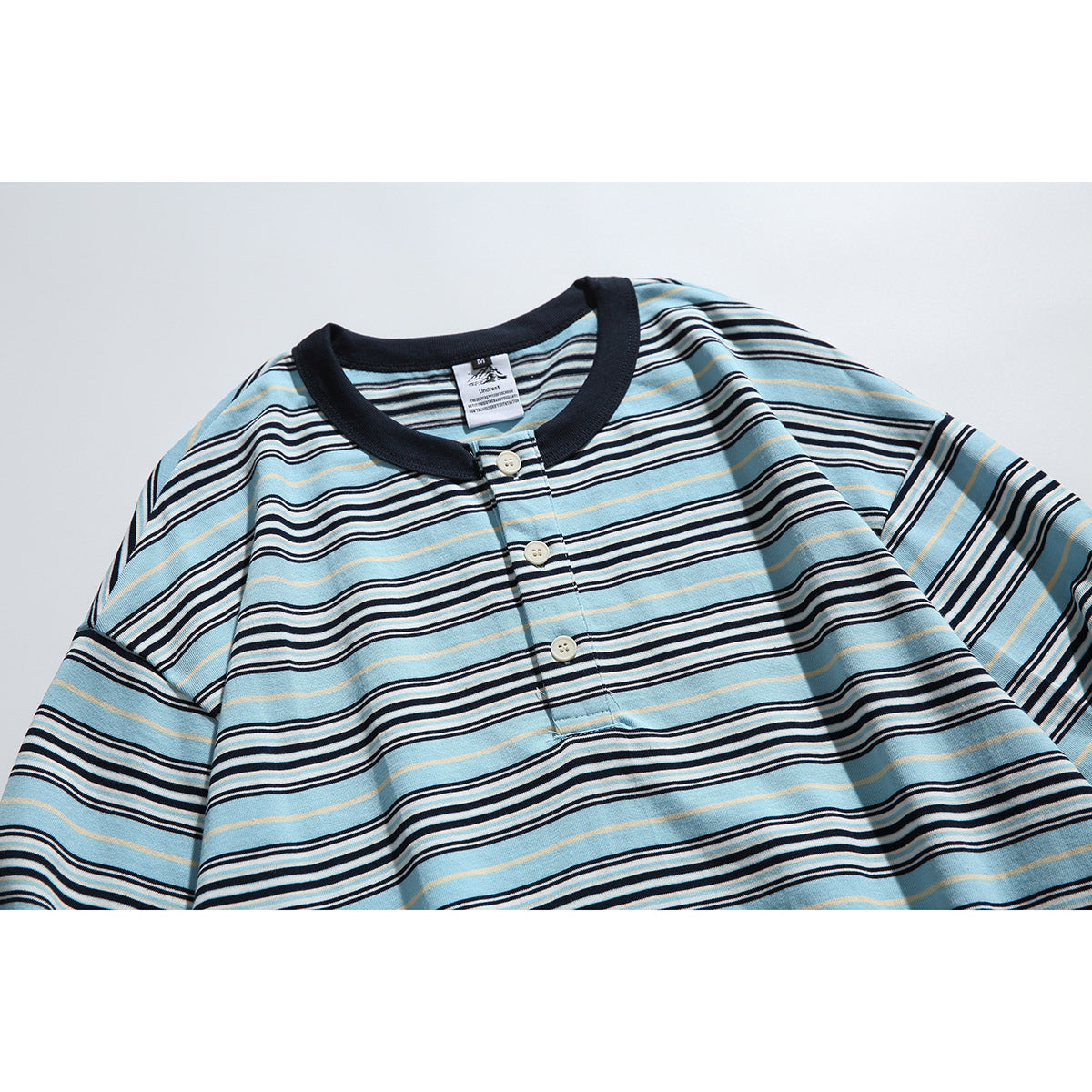 Flat-lay front of a blue long-sleeve striped henley shirt with a dark collar and three buttons.