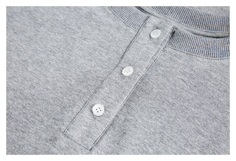 Close-up of the heather gray top's three white buttons and front placket beside the ribbed neckline.
