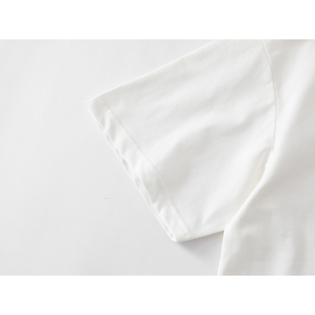 Close-up of the short sleeve and stitched hem of a white T-shirt.