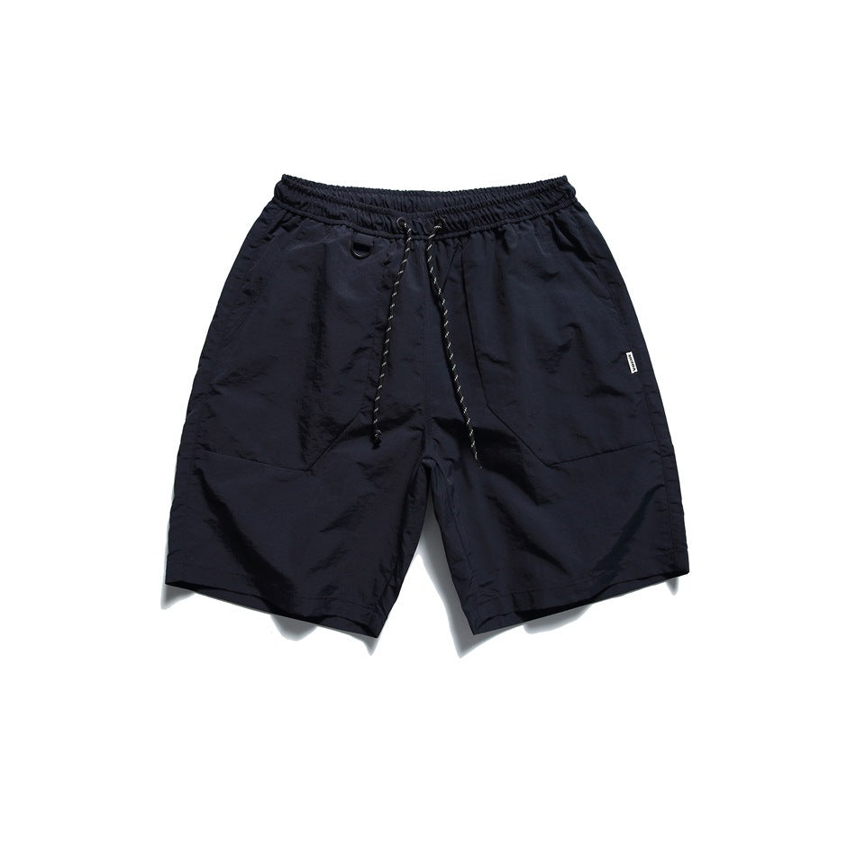 Navy drawstring shorts with crinkled matte fabric, front pocket panels and a D-ring, flat lay front view
