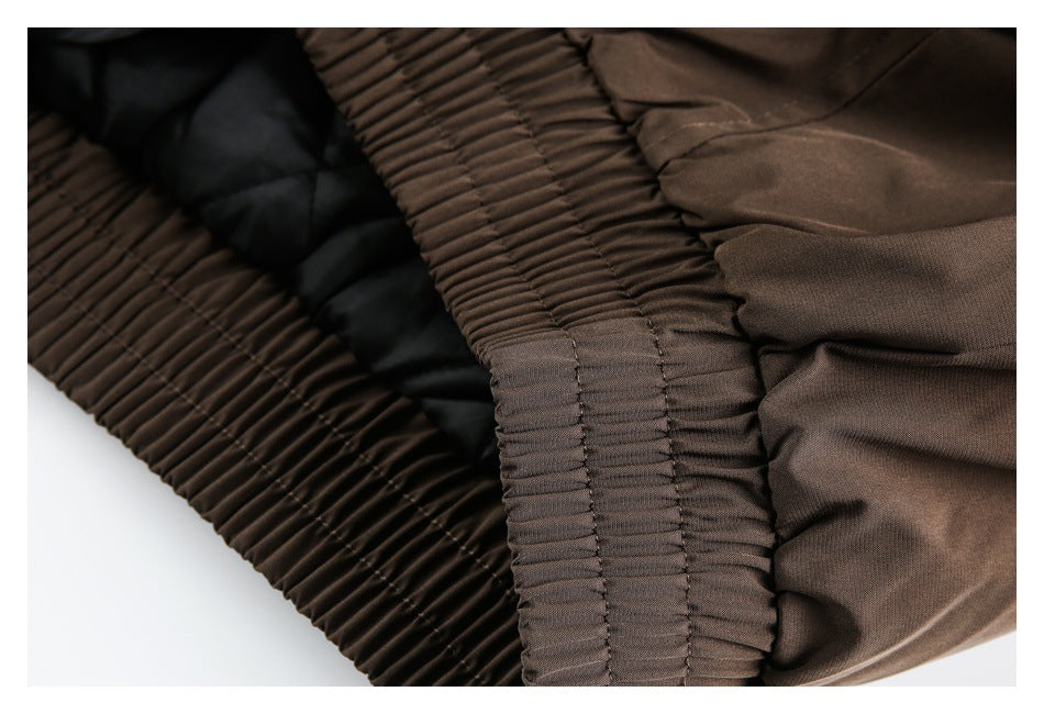 Close-up of the brown jacket's gathered elasticized hem and smooth outer fabric.