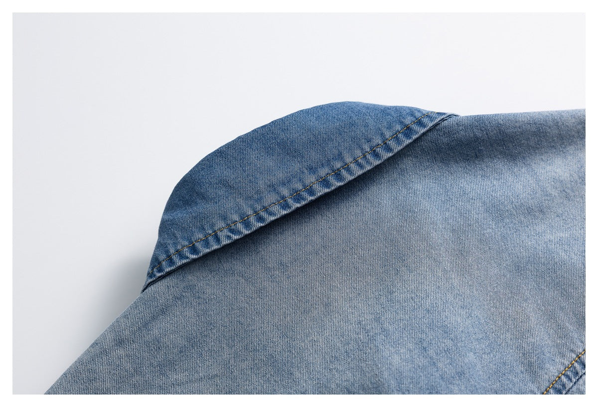 Close-up of a blue denim shirt collar seam and faded fabric texture.