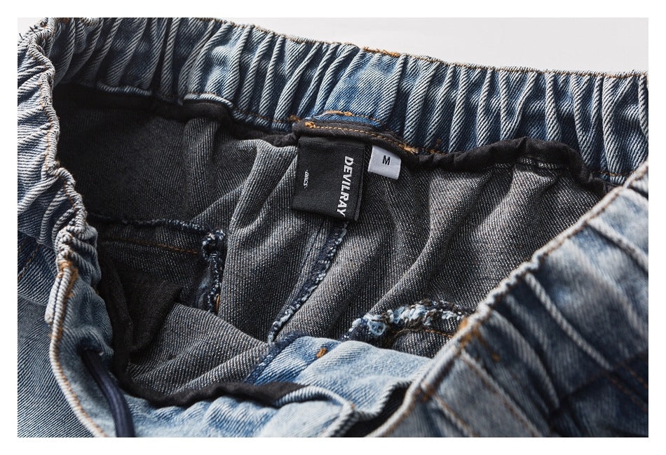 Close-up of the inside of the denim pants showing the gathered waistband and sewn-in brand and size labels.